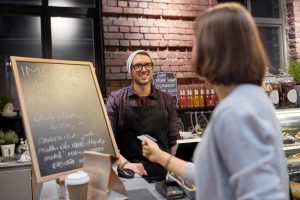 barman and woman paying with credit card at cafe